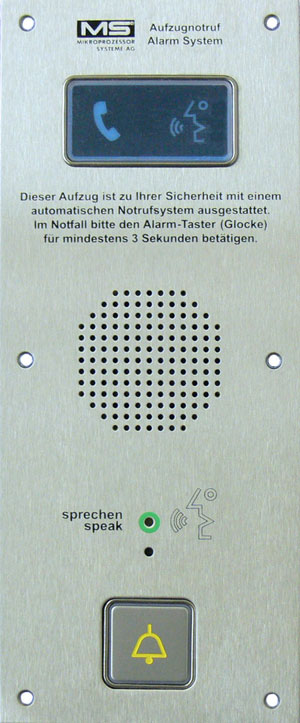 Metallische Aufzug-Notrufsprechstelle mit Display, Lautsprechergitter, Bedienungshinweisen und einer Ruftaste mit gelbem Glockensymbol.