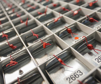 Zahlreiche kleine Metallfächer in einem Raster, die jeweils versiegelte Gegenstände mit roten Plomben und Nummern wie 2663 enthalten.